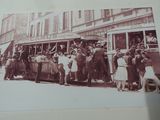 une photo en noir et blanc d'un groupe de personnes debout devant un bus