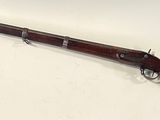 an old rifle with a wooden barrel on a white surface