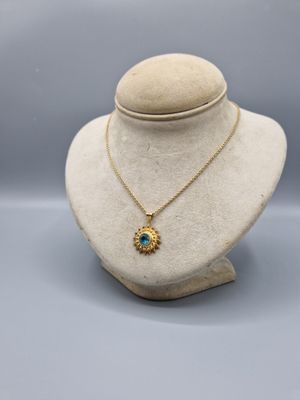 un collier en or avec un pendentif en pierre bleue sur un mannequin