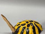 a small yellow and black turtle toy on a white surface