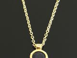 a gold necklace with a black stone on a chain