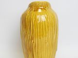 a yellow vase that is sitting on a white surface