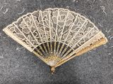 an old fan with a lace pattern hanging from it ' s side