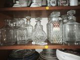 many glass jars and plates on a shelf in the kitchen