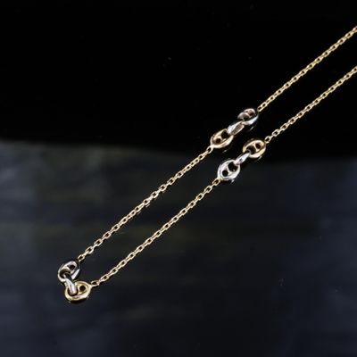 une paire de colliers à chaîne en or posés sur une surface noire