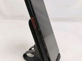 the back of a black cell phone on a stand on a white surface