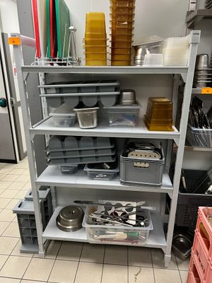 une étagère sur laquelle sont posés de nombreux récipients et casseroles, dans une cuisine