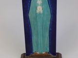 a statue of the virgin mary of guadalupe on a wooden base