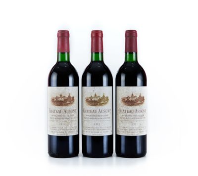 trois bouteilles de vin rouge posées l'une à côté de l'autre sur une surface blanche