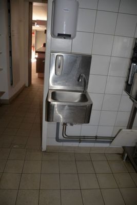 une salle de bains équipée d'un lavabo et d'un sèche-mains fixé au mur