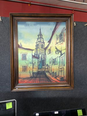 une photo d'un tableau accroché au mur au-dessus d'un ordinateur portable