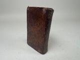 an old brown leather book sitting on top of a white table