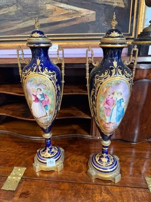 deux vases posés sur une table devant un tableau