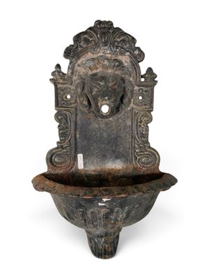 une vieille fontaine en métal surmontée d'une tête de lion