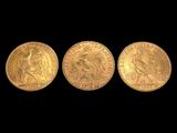 three gold sovereigns, one of which is the head of a woman and one of which is a man