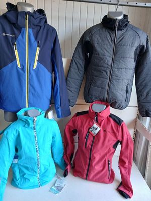 trois vestes exposées dans un magasin de vêtements, sur une table blanche