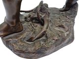 bronze statue of a person standing on a rock with a foot on it