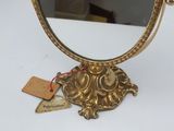 a gold mirror on a white table with a tag on it