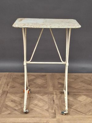 une vieille table blanche à roulettes posée sur un parquet