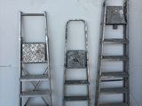several ladders are lined up against a white wall in a room