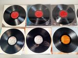 six black vinyl records are lined up on a white surface