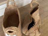 paire de paniers en jute naturel avec des anses, posés sur un sol en bois