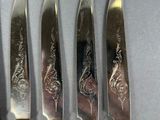 four knives with a silver handle are lined up on a table