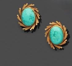 une paire de boucles d'oreilles en turquoise et or sur un fond noir