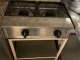une cuisinière à deux feux sur laquelle est posée une casserole