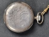 a silver pocket watch with a chain on a black surface
