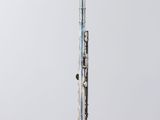 silver flute on a clear acrylic stand against a white background