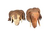 pair of carved wooden ram head sculptures on a white surface