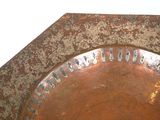 a rusted metal plate on a table with a white wall in the background