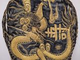 une image représentant une pièce noire et dorée sur laquelle figure un dragon