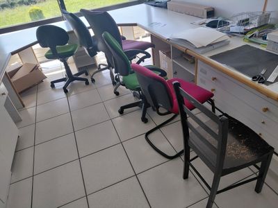 plusieurs chaises et un bureau dans une pièce dotée d'une fenêtre