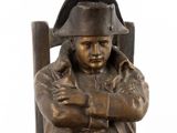 bronze statue of a man with a hat on his head sitting on a chair