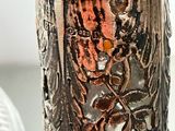 a close up of a silver vase with a flower design on it
