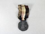 an old medal on a white surface with a ribbon around it