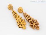 pair of gold earrings with flowers and leaves on a white surface