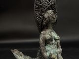 a bronze statue of a woman with a basket on her head