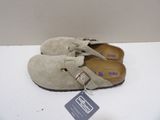 pair of beige sued clogs with buckles and a tag on a white surface