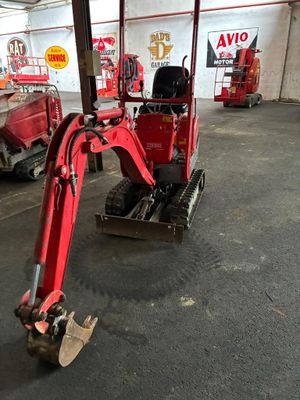 une photo d'une petite pelleteuse rouge dans un garage