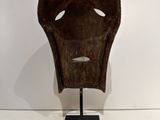 an image of a wooden mask on a stand in a white room