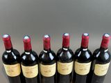 six bottles of red wine lined up in a row