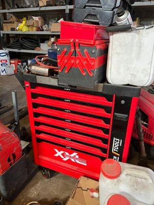 une boîte à outils rouge posée sur une pile d'outils