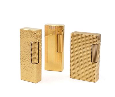 three gold colored lighters sitting next to each other on a white surface