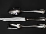 three forks and a knife on a black table