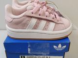 une paire de baskets Adidas roses et blanches posées sur une boîte bleue