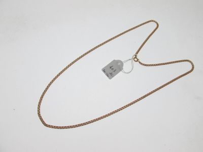 une chaîne en or à laquelle est accrochée une médaille, posée sur une surface blanche