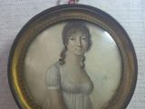 an old picture of a woman in a white dress is hanging on a wall
